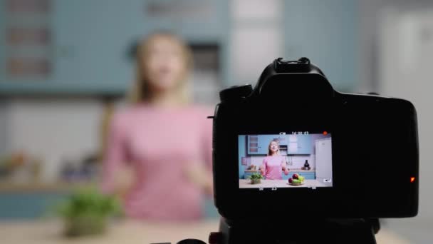 Молода жінка розмовляє з камерою про переваги овочів, вітамінів та здорової дієти. Жіночий блогер, який знімає історії на кухні для блогу приготування їжі в соціальних мережах. Повільний рух готовий, 4K на 59.97fps . — стокове відео