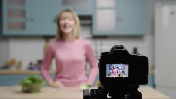 Jovem mulher fala para a câmera sobre os benefícios de usar manchas de olhos em vez de pepinos. Blogueira feminina filmando histórias na cozinha para blog de beleza de mídia social. Movimento lento pronto, 4K a 59.97fps. — Vídeo de Stock