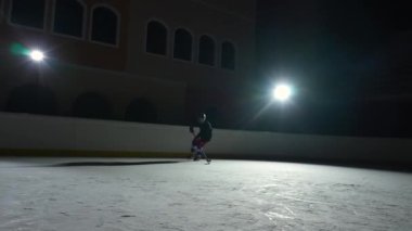 Profesyonel forvet oyuncusu usta bir şekilde top sürüyor, puck 'a sopa puanı golüyle vuruyor. Hokey diski ağa çarptı. Karanlık buz arenasında spot ışıklarıyla hokey oynayan bir atlet. Yavaş çekim.