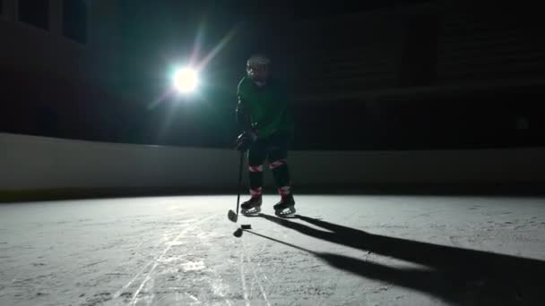 Tiefwinkel-Hockeyspieler dribbelt meisterhaft und trifft den Puck mit dem Stock ins Tor. Eishockey-Puck landet im Netz. Ein Sportler spielt Hockey auf einer dunklen Eisarena mit Scheinwerfern. Zeitlupe. — Stockvideo