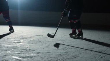 İki erkek hokey oyuncusu ustaca top sürüyor, sopayla puck 'a vuruyor ve gol. Hokey diski ağa çarptı. Sporcular karanlık buz arenasında spot ışıklarıyla hokey oynarlar. Ağır çekim. Kapat..