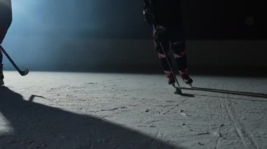 İki erkek hokey oyuncusu ustaca top sürüyor, sopayla puck 'a vuruyor ve gol. Hokey diski ağa çarptı. Sporcular karanlık buz arenasında spot ışıklarıyla hokey oynarlar. Ağır çekim. Kapat..