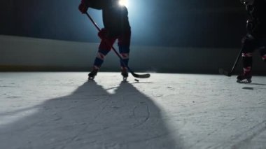 İki erkek hokey oyuncusu ustaca top sürüyor, sopayla puck 'a vuruyor ve gol. Hokey diski ağa çarptı. Sporcular karanlık buz arenasında spot ışıklarıyla hokey oynarlar. Ağır çekim. Kapat..