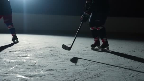 Two men hockey player masterfully dribbles, hitting puck with stick and forward scores goal. Hockey puck hits the net. Athletes plays hockey on dark ice arena with spotlights. Slow motion. Close up. — Stock Video