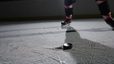 Profesyonel bir forvet diske hokey sopasıyla vurur ve bir sürü buz tozu yaratır. Hokey oyuncusu karanlık ve aydınlık bir buz arenasında vuruş talimi yapıyor. Sinema yavaş çekim. Kapat..