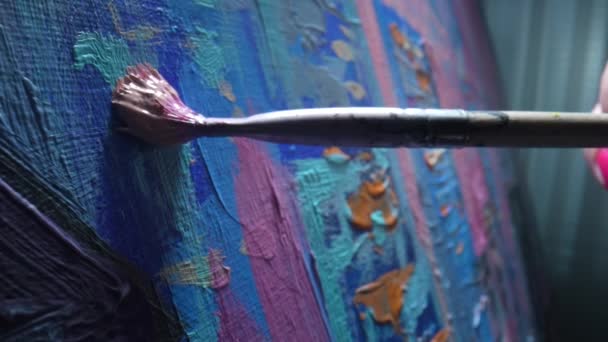 Künstler pinseln Ölgemälde auf Leinwand. Nahaufnahme Pinsel trägt Pinselstriche von rosa Farbe auf die Leinwand auf. Künstler zeichnet zeitgenössische Kunst in einer kreativen Werkstatt. Unterricht in der Kunstschule. Zeitlupe. — Stockvideo