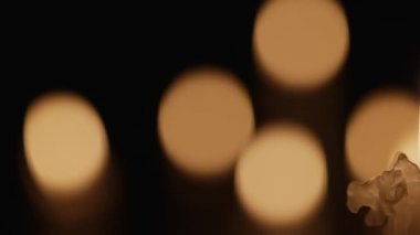 Mumları yakan mumlar, bulanık mum ışığı efektiyle siyah bir arkaplanda yanıp sönüyor. Geçmiş ya da anma, yas tutma ya da kutlama. Kilisede mum yakın..