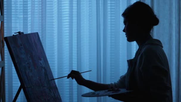 女性画家在画布上画油画，并在艺术工作室创作艺术品的轮廓。女人在调色板上用刷子刷油漆，然后用笔画。慢动作靠近点. — 图库视频影像