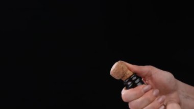 Kadın eli siyah arka planda şampanya şişesinin tıpasını açıyor. Köpüklü köpüklü köpüklü köpüklü beyaz şarap patlaması yavaş çekimde kapanır. Tatil, yeni yılı kutlamak, doğum günü partisi.