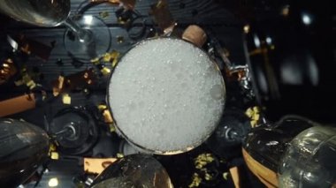 Yukarıdan ve içeriden köpüklü köpüklü şampanya bardağının görüntüsü. Kamera hareketiyle beyaz şarabı şişeden bardağa dolduruyorum. Doğum günü için şenlik arka planı. Yavaş çekim