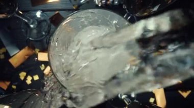 Köpüklü köpüklü köpüklü şampanya bardağının manzarası. Şişeden bardağa dökülen ve dökülen beyaz köpüren şarap akımını çok yakından takip et. Doğum günü için şenlik arka planı. Yavaş çekim.