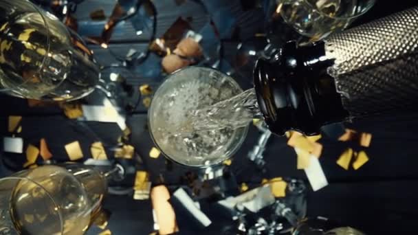 泡と泡で輝くシャンパンを注ぐのトップガラスからの眺め。超クローズアップカメラの動きでボトルからガラスに白ワインを注ぐ。誕生日のためのお祭りの背景。スローモーション. — ストック動画