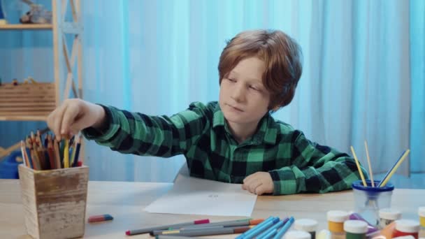 Malý školáček sedící u stolu v pokoji a kreslící tužkou na albu. Teenager chlapec se zabývá kreativitou, kreslí obrázek, koníček, vývoj. Zavřít. Zpomalení připraveno, 4K při 59,94fps. — Stock video