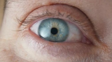 Mavi iris ve retinası olan güzel bir erkek gözü. Gözlerinde korku, korku, korku, korku gözlerini açıyor. Gri göz, göz bebeğine ve gözbebeğine yakın. Sağlıklı görme konsepti. Yavaş çekim.