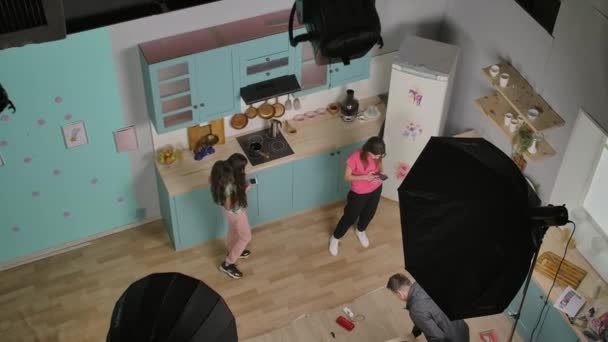 Backstage-Videodreh im Kinopavillon. Glückliche junge Mädchen Blogger singen Lied, mit dem Handy machen Tanzvideo in der Küche. Prozess der Erfassung von Trendinhalten für Social-Media-Konten — Stockvideo