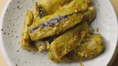 Tempura patlıcanlarının baharatlı ve kamış şekerli dilimlerinin üst görüntüsü. Gri tabakta kıtır kıtır patlıcan parçaları, yakından dönüyor. Sıcak baharatla yağda kızartılmış sebzeler. Yavaş çekim.