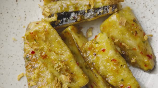 Vue de dessus des tranches d'aubergine tempura avec des épices épicées et du sirop de sucre de canne. Les morceaux d'aubergine croustillants frits sur une assiette grise se referment. Servir la vaisselle. Restaurant avec cuisine traditionnelle japonaise. Mouvement lent. — Video