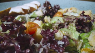 Ördek, domates, marul, kızarmış ekmek ve peynirli taze sezar salatası. Gri tabakta etli ve lezzetli soslu sebze sulu salata. Sağlıklı yemekler, restoran yemekleri. Kamera yavaş çekimde yakınlaştır.