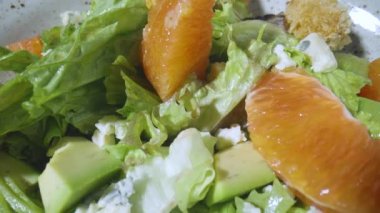 Greyfurtlu salata, yeşil marul, avokado, ton balığı, gri tabakta peynir, yakından dönüyor. Restoran yemeği, sağlıklı sebze, meyve ve et. İtalyan salatası. Fransız mutfağı. Yavaş çekim.