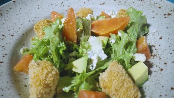 Salad with grapefruit, green lettuce, avocado, tuna, cheese on gray plate, rotating close up. Restaurant food, healthy dish of vegetables, fruits and meat. Italian salad. French cuisine. Slow motion. — Stock Video