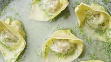 Çorbanın en üst manzarası, yakın plan gri tabakta dönen mantarlar. Çin mantısı, üzerine dereotu ve baharat serpiştirilmiş. Dim Sum buharlı börek. Çin lokantası mutfağı. Yavaş çekim.