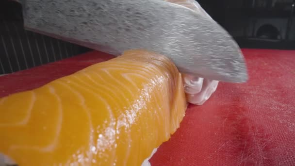 Processo de cozinhar sushi rolo Filadélfia de perto. Mestre Sushi corta o rolo em pedaços com uma faca afiada. Comida tradicional japonesa com frutos do mar e peixe. Cozinha asiática. Sushi pronto. Movimento lento. — Vídeo de Stock