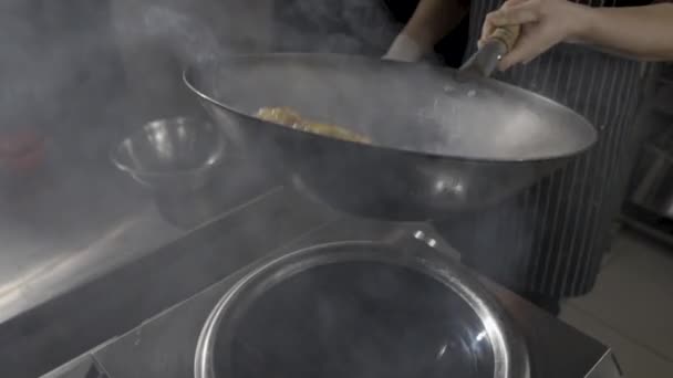 Chef d'un restaurant asiatique frites aubergine dans une poêle chaude sur le fond de la cuisine. Un homme fait frire des légumes dans de l'huile avec des épices chaudes, de l'ail et du sirop de sucre de canne. Au ralenti. Gros plan. — Video