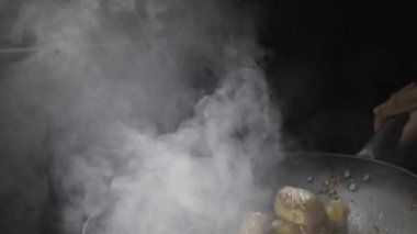 Asya restoranındaki bir restoranın aşçısı, patlıcan kızartması ve sıcak kızartma tavası onları mutfağın arka planına fırlatıyor. Adam yağda sebze kızartıyor sıcak baharat, sarımsak ve şeker şurubuyla. Ağır çekim. Kapat..