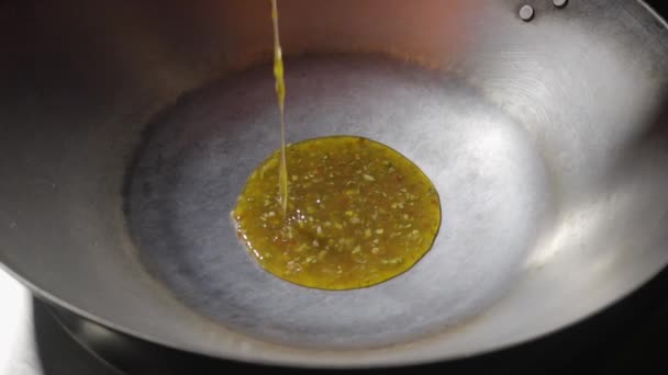 Λάδι με μπαχαρικά και σκόρδο χύνεται σε ένα προθερμασμένο τηγάνι γουόκ και τα κομμάτια της μελιτζάνας σε tempura χύνεται. Μαγειρεύοντας ένα πικάντικο ασιατικό πιάτο μελιτζάνας λαχανικών. Τηγάνι τηγανίσματος από κοντά. Αργή κίνηση. — Αρχείο Βίντεο