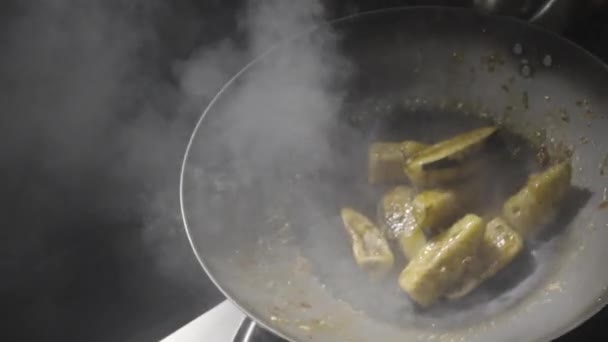 Chef de um restaurante asiático frita berinjela na frigideira quente jogando-os no fundo da cozinha. O homem frita legumes em óleo com especiarias quentes, alho e xarope de açúcar. Movimento lento. Fechar. — Vídeo de Stock