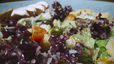Ördek, domates, marul, kızarmış ekmek ve peynirli taze sezar salatası. Gri tabakta etli ve lezzetli soslu sebze sulu salata. Sağlıklı yemekler, restoran yemekleri. Kamera yavaş çekimde yakınlaştır.