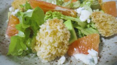 Greyfurtlu salata, yeşil marul, avokado, ton balığı, gri tabakta peynir, yakından dönüyor. Restoran yemeği, sağlıklı sebze, meyve ve et. İtalyan salatası. Fransız mutfağı. Yavaş çekim.