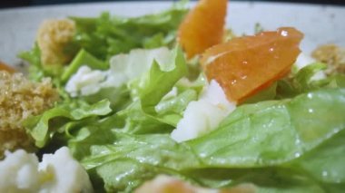 Greyfurtlu salata, yeşil marul, avokado, ton balığı, gri tabakta peynir, yakından dönüyor. Restoran yemeği, sağlıklı sebze, meyve ve et. İtalyan salatası. Fransız mutfağı. Yavaş çekim.