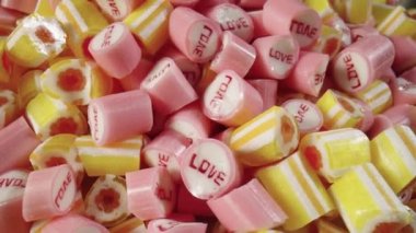 Renkli çizgili karamelli şekerler çeşitli, dönüşümlü çekim. Pembe ve sarı lolipopların karışımı. Tatlı tatlı. Şekerci. Şenlik arka planı. Yavaş çekim hazır, 4K 59.94fps 'de..