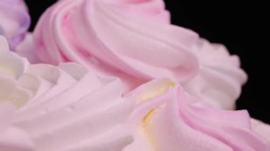 Siyah arka planda dönen tatlı kremalı pasta. Protein ve şekerden yapılmış Fransız kurabiyeleri. Şekerli tatlı sarısı, pembe ve mor renkli. Yavaş çekim hazır, 4K 59.94fps 'de.