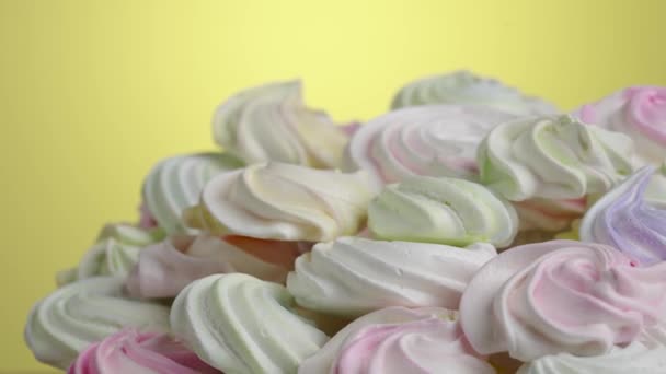 Wiry słodkiej bezy obracające się na żółtym tle. Słodki bezy żółty, różowy i fioletowy kolor w słodycze. Zamknij kieliszek białka i ciasteczka z cukrem. Zwolnij, 4K przy 59,94fps.. — Wideo stockowe