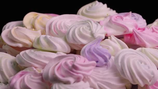 Draai van zoete meringue draaien op zwarte achtergrond. Franse zoetigheden koekjes gemaakt van eiwit en suiker. Close-up shot van snoep dessert geel, roze en paars kleur. Slow motion klaar, 4K bij 59,94fps — Stockvideo