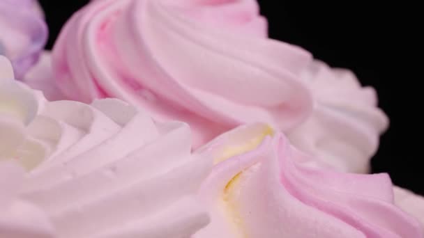 Forog az édes habcsók forog a fekete háttér. Fehérjéből és cukorból készült francia édességsütik. Közelkép cukorka desszert sárga, rózsaszín és lila színű. Lassú mozgás kész, 4K 59.94fps-on. — Stock videók