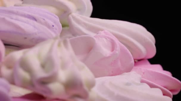 Draai van zoete meringue draaien op zwarte achtergrond. Franse zoetigheden koekjes gemaakt van eiwit en suiker. Close-up shot van snoep dessert geel, roze en paars kleur. Slow motion klaar, 4K bij 59,94fps — Stockvideo