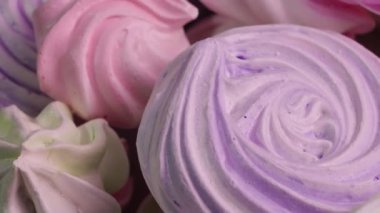 Tatlı kremalı pasta dönüşleri yakından dönüyor. Fransız tatlıları, protein ve şekerli kurabiyeler pembe ve mor renkli. Çocukların doğum günü için şekerlerin şenlikli arka planı. Yavaş çekim hazır, 4K 59.94fps 'de..