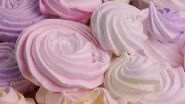 Draaiingen van zoete meringue draaien van dichtbij. Franse zoetigheden, van eiwit en suiker koekjes roze en paarse kleur. Feestelijke achtergrond van snoepjes voor kinderen verjaardag. Slow motion klaar, 4K bij 59,94fps. — Stockvideo