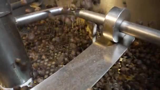 Οι κόκκοι καφέ χύνεται σε μια βιομηχανική μηχανή ψησίματος καφέ σε ένα εργοστάσιο. Ανακατεύω καβουρδισμένους κόκκους καφέ. Αρωματικά καφέ φασόλια στροβιλίζονται από κοντά. Φαγητό και ποτό φόντο για καφέ. Αργή κίνηση. — Αρχείο Βίντεο