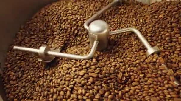 갓 볶은 커피 열매의 생산. 산업용 믹 싱 머신은 볶은 커피 콩을 로커 스터에 넣고 닫습니다. 공장에서 커피를 볶는 과정. 카페를 위한 음식 과 음료의 배경이다. 느린 동작. — 비디오
