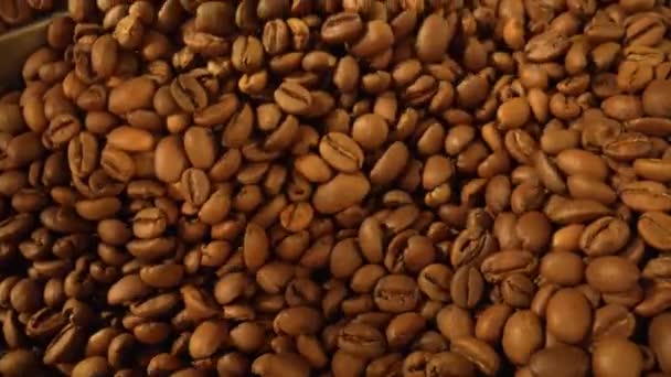 Παραγωγή φρεσκοψημένων κόκκων καφέ. Μίξη, ψήσιμο και ψύξη κόκκων καφέ σε μια βιομηχανική μηχανή σε ένα εργοστάσιο. Αρωματικά καφέ φασόλια στροβιλίζονται από κοντά. Ιστορικό για καφέ. Αργή κίνηση. — Αρχείο Βίντεο