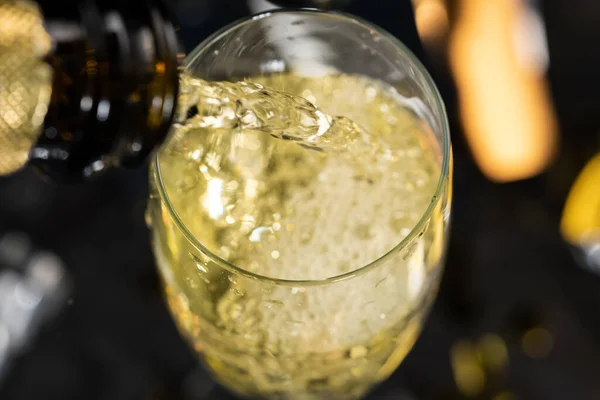 Blick vom obersten Glas prickelnden Champagners mit Blasen und Schaum. Aus nächster Nähe Weißwein aus der Flasche ins Glas gießen. Festlicher Hintergrund für Geburtstag, Neujahr, Feiertag, Siegesgratulation. — Stockfoto