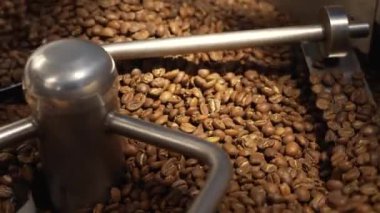 Kahve kızartma makinesinde kahve kızartılıyor. Kavrulmuş döner soğutucu profesyonel makineler ve fabrikada kahverengi kahve çekirdekleri hareketi. Kafe için yiyecek ve içecek arka planı. Yavaş çekim.