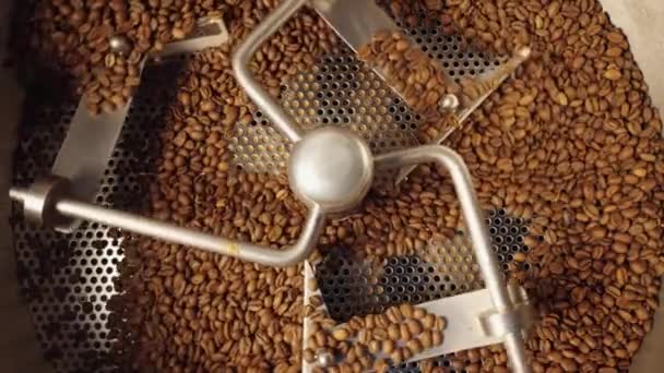 Production de grains de café fraîchement torréfiés. Mélange, torréfaction et refroidissement des grains de café dans une machine industrielle en usine. Haricots bruns tourbillonnant de près. Contexte pour café. Vue de dessus. Mouvement lent. — Video