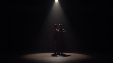 Kadın ve erkek, üstlerindeki ışıkla karanlıkta Latin dansı yapıyorlar. Karanlık arka planda tutkuyla dans eden iki dansçının siluetleri. Yavaş çekim hazır, 4K 59.94fps 'de..