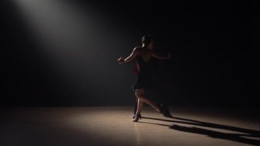 Çift dansçılarının silueti karanlıkta dumanla ve spot ışıklarıyla tango yapıyor. Bir çift balo dansçısı. Latin Amerika dansları okulunda koreografi dersi. Yavaş çekim hazır, 4K 59.94fps 'de..