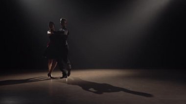Tutkulu Arjantin tangosu iki dansçı tarafından icra edildi. Siluet adam ve bir kadın karanlıkta ışıklar ve dumanla Latince dans ediyorlar. Yavaş çekim hazır, 4K 59.94fps 'de..